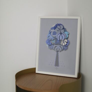 blue geometrical tree small poster in a white frame on a wooden table