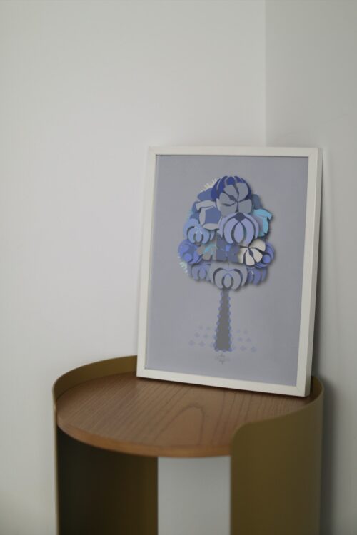 blue geometrical tree small poster in a white frame on a wooden table