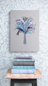 blue palm tree wall decor above stack-of-books-on-wooden-stool