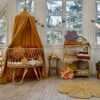 Light nursery in brown - rattan Moses basket with brown canopy over it and flower floor yellow mat