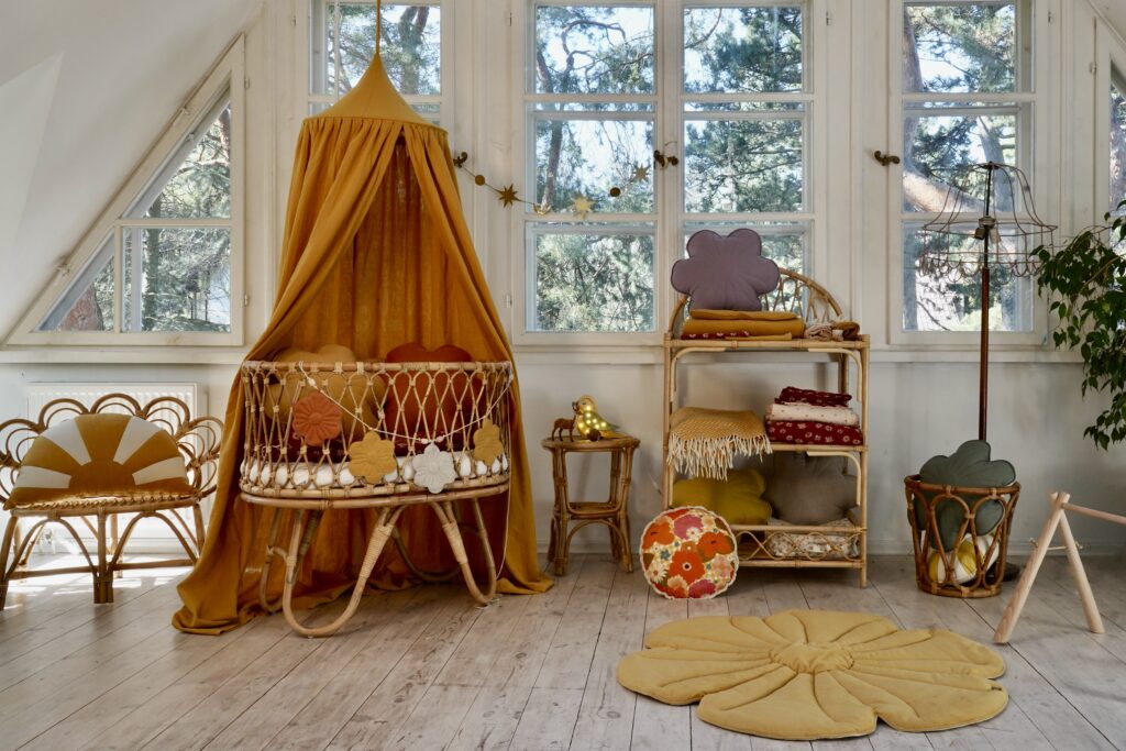 Light nursery in brown - rattan Moses basket with brown canopy over it and flower floor yellow mat