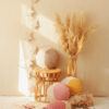 collection of colourful moon pillows - yellow, dusty pink and beige on a wicker chair