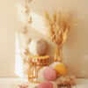 collection of colourful moon pillows - yellow, dusty pink and beige on a wicker chair