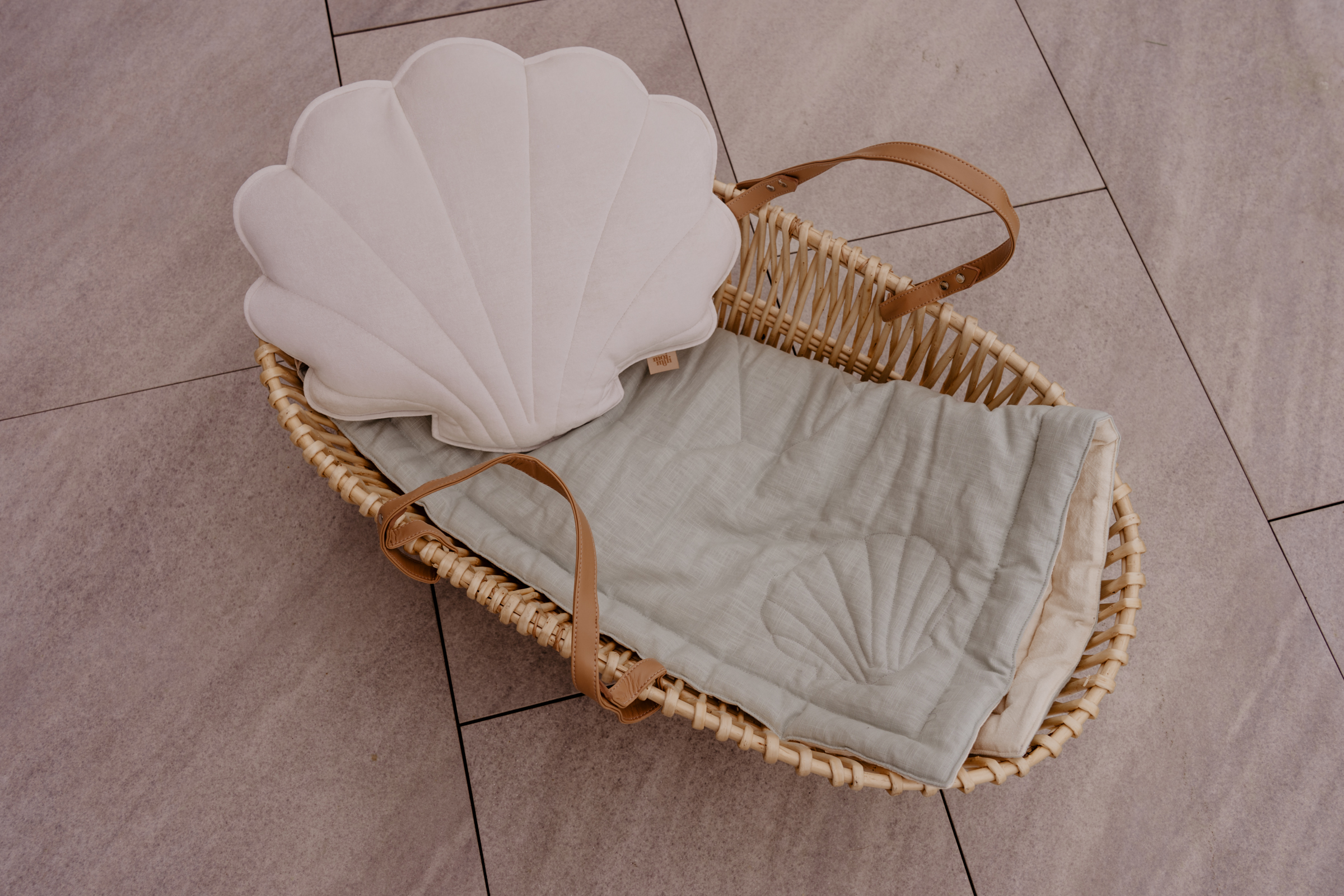 white velvet shell pillow in a moses basket
